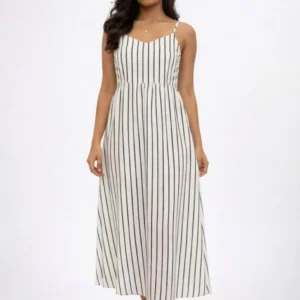 A model wears a sleeveless white dress with black stripes, standing against a plain background.